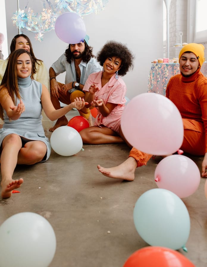 Friends at an indoor party with colorful balloons