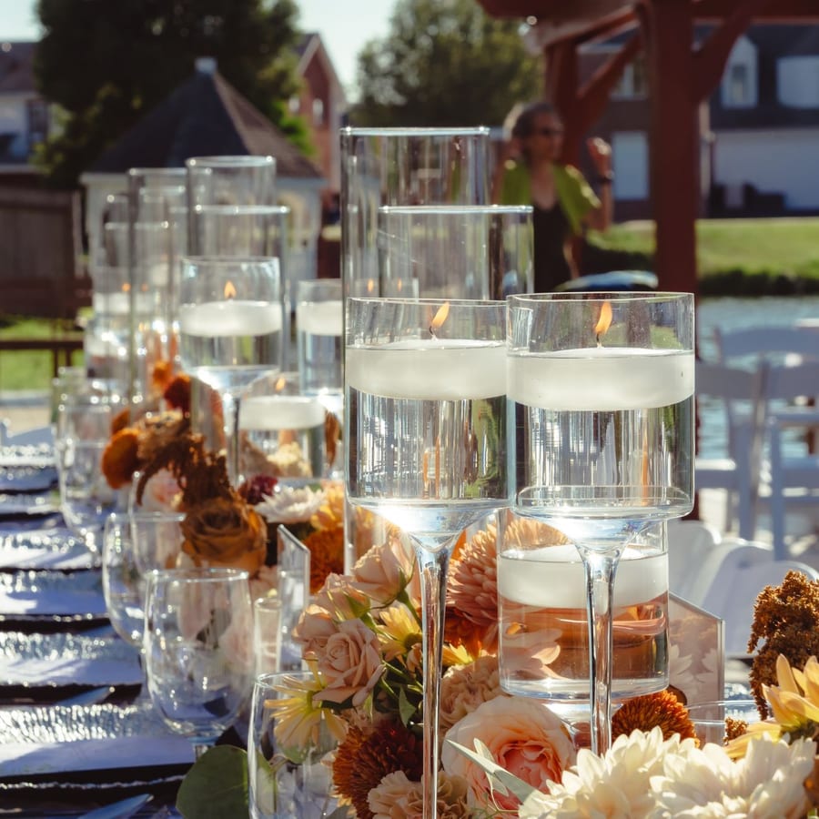 A table set with flowers and candles at an outdoor wedding