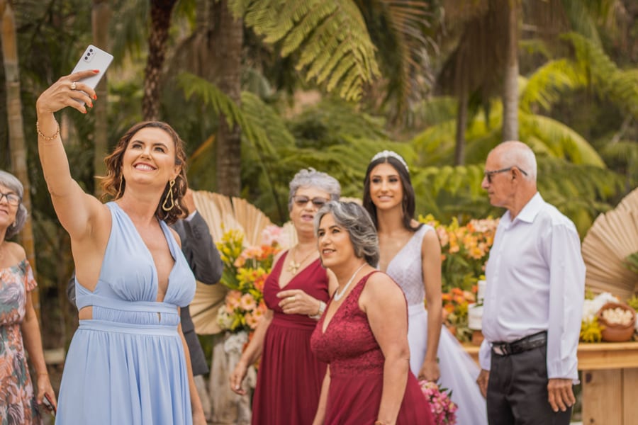 Wedding guests gathering for a group selfie at an outdoor reception